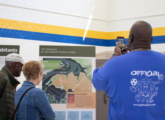 A group of residents looking at large informational posters about Latta.