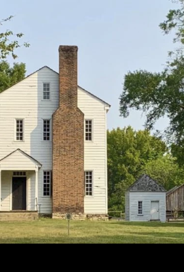 Una casa con una gran chimenea en una zona forestal.